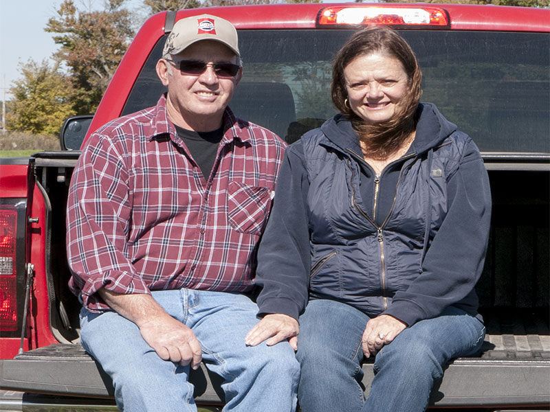 Jim and Peg Merriman sitting on the bed of a truck